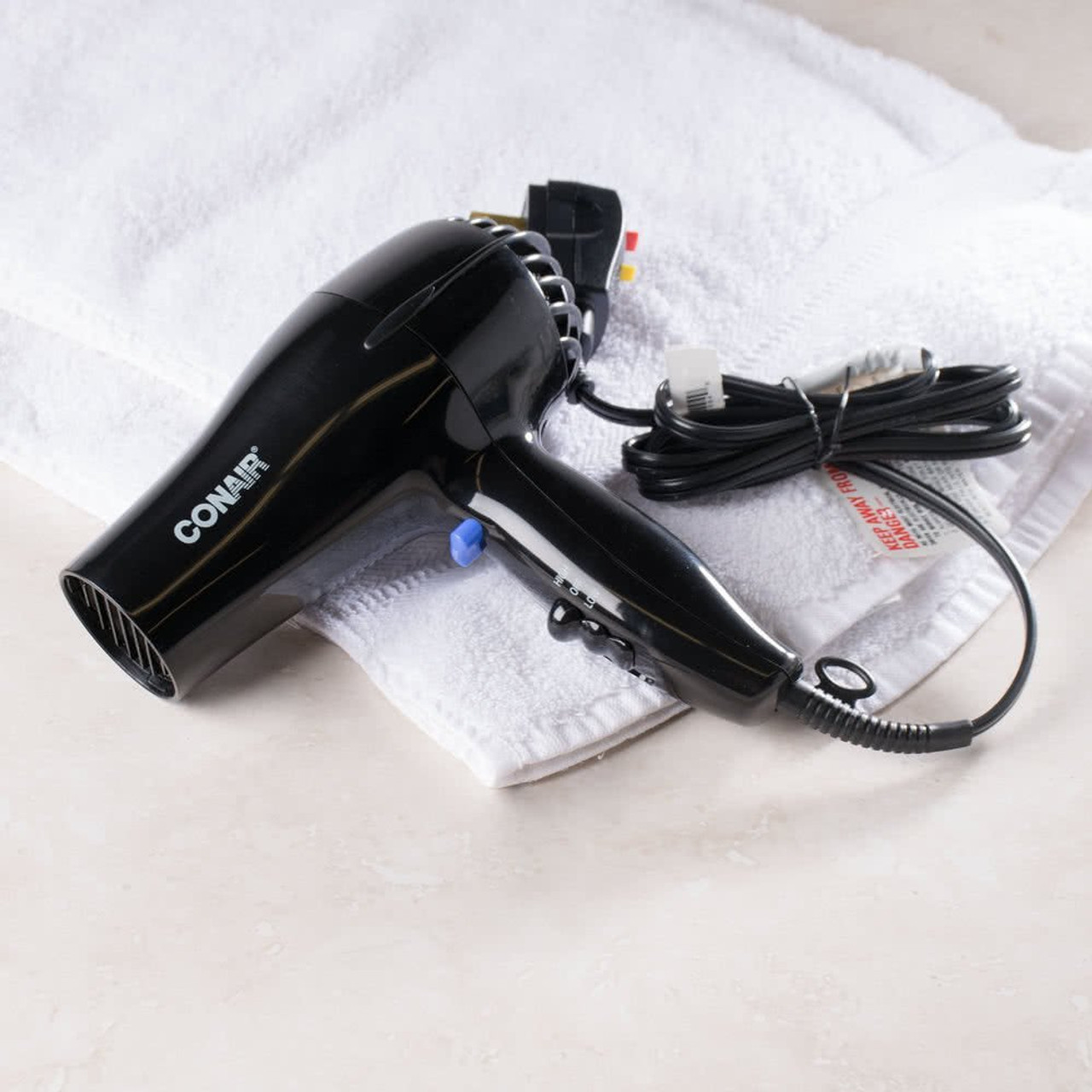 Black Conair hospitality hair dryer on a white towel.