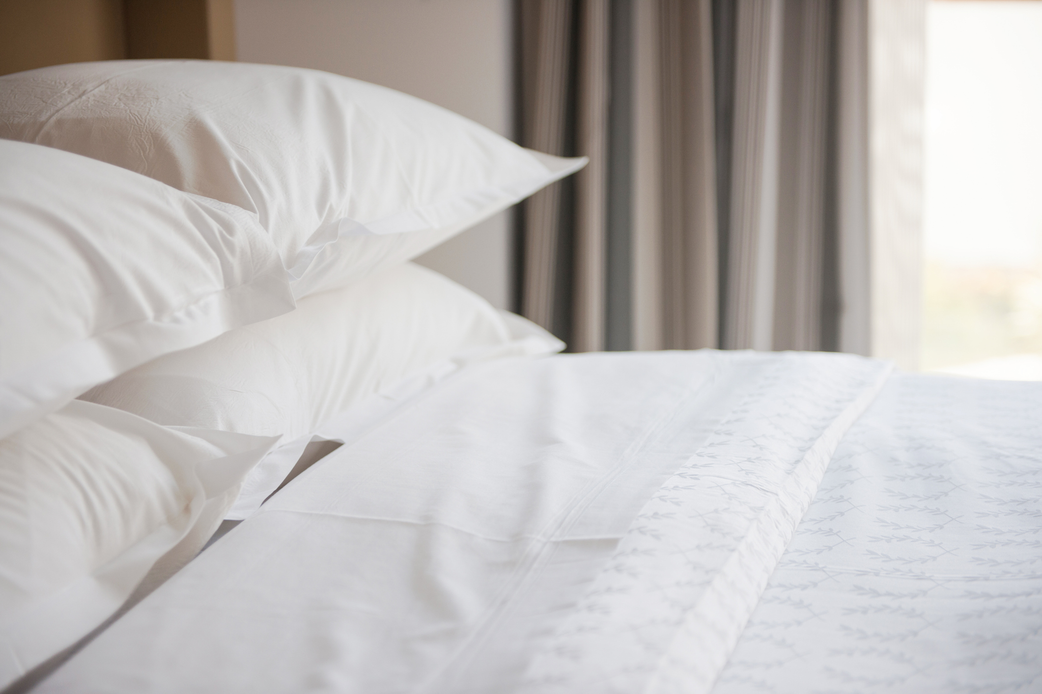 A neatly made bed with crisp hospitality sheets
