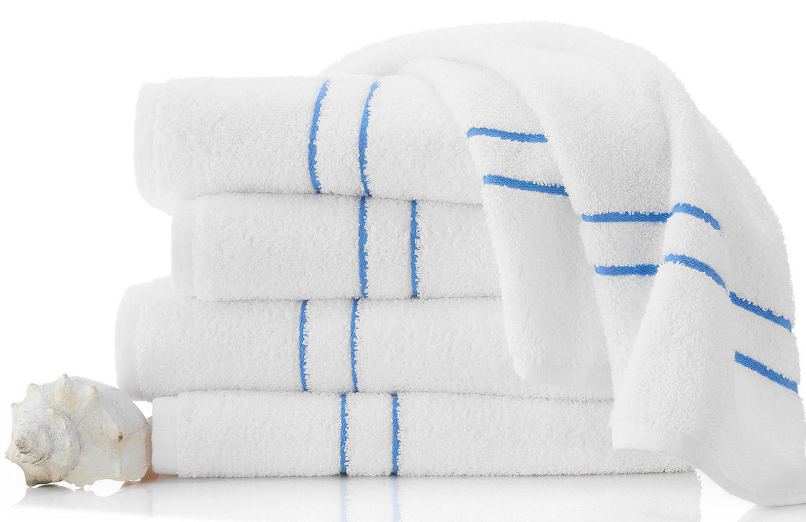 Four neatly folded white towels stacked on one another with a fifth towel draped along the top of the stack.