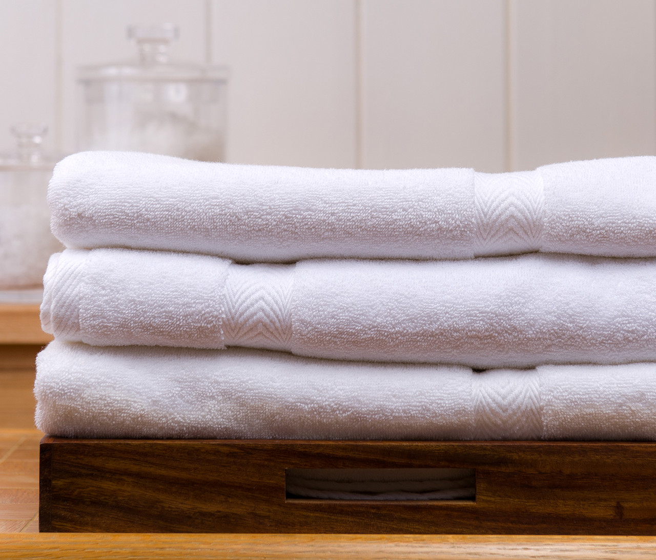 Three folded white towels on a wooden tray