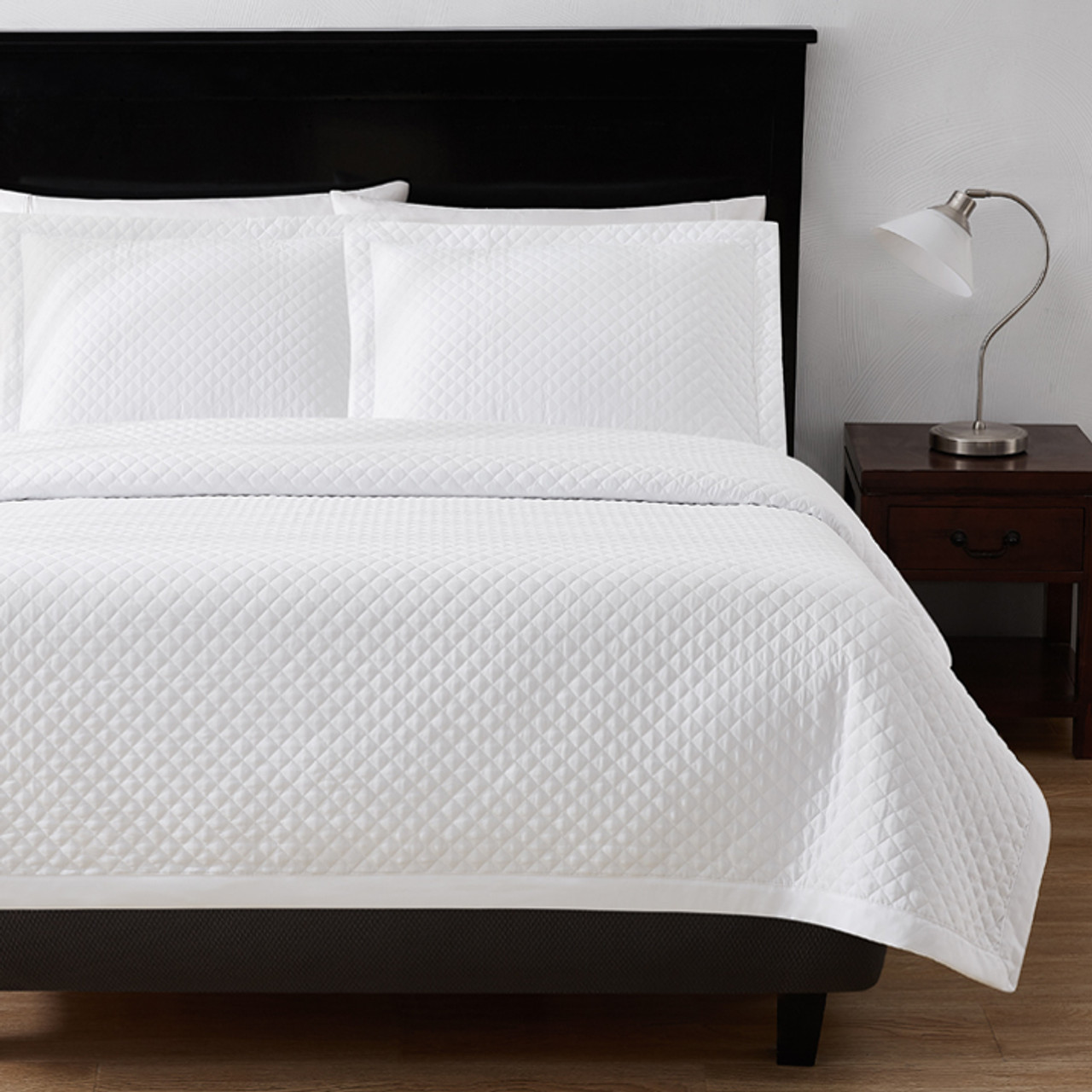 Radiance White Diamond Quilt on bed with dark wooden accents